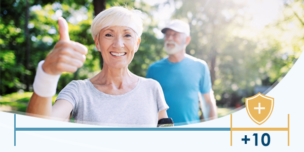 Older woman giving a thumbs up and an older man in the background