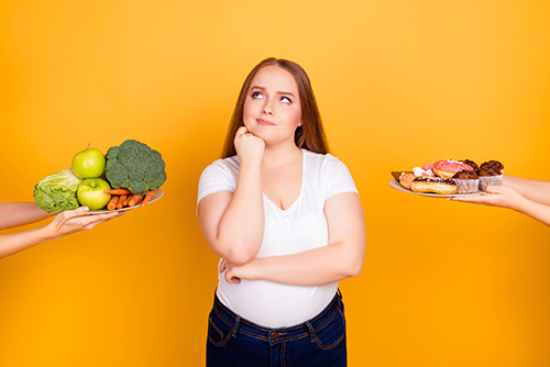 Female choosing between healthy and unhealthy food