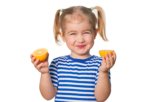 Little girl holding two half lemons